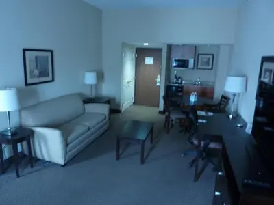 a living room with a couch and a desk in a hotel room at Wingate by Wyndham Erlanger - Florence - Cincinnati South in Erlanger