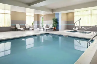 a pool in a hotel room with chairs and tables at Hilton Garden Inn Toledo / Perrysburg in Perrysburg