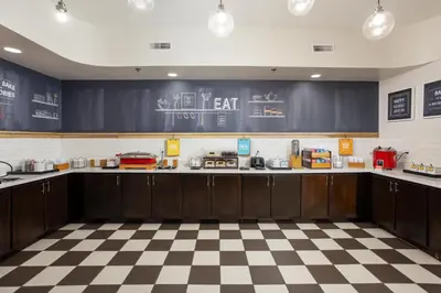 a kitchen with dark wood cabinets and a checkered floor at Hampton Inn Carrollton KY in Carrollton