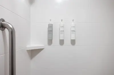 a shelf in a bathroom with three bottles on it at Hampton Inn Carrollton KY in Carrollton