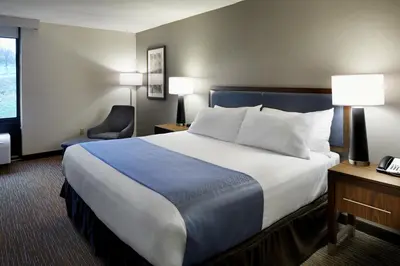 a hotel room with a large bed and a chair at Wingate by Wyndham St. Clairsville/Wheeling in Saint Clairsville