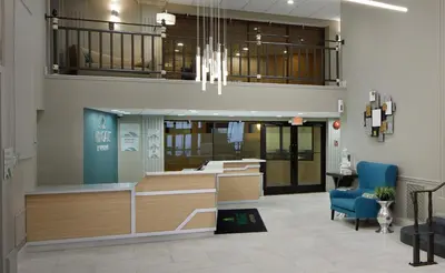an office lobby with a reception desk and a blue chair at Wingate by Wyndham St. Clairsville/Wheeling in Saint Clairsville