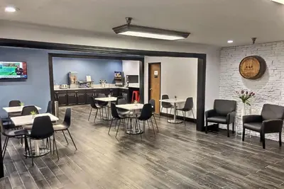 a dining room with tables and chairs and a kitchen at Super 8 by Wyndham Georgetown in Georgetown