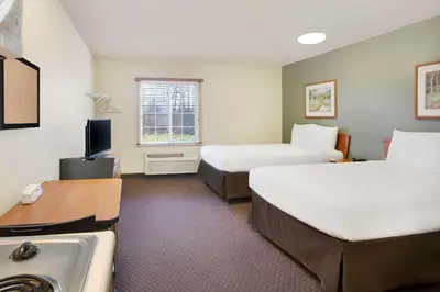 a hotel room with two beds and a sink at WoodSpring Suites Cincinnati Fairfield in Fairfield