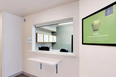 a hospital room with a table and a mirror at WoodSpring Suites Cincinnati Fairfield in Fairfield