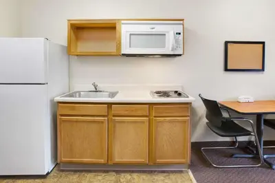 a kitchen with a sink and a microwave and a table at WoodSpring Suites Cincinnati Fairfield in Fairfield