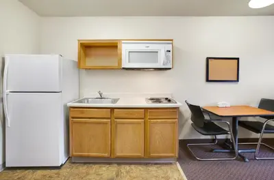 a kitchen with a refrigerator and a sink and a table at WoodSpring Suites Cincinnati Fairfield in Fairfield