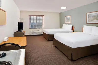 a hotel room with two beds and a sink at WoodSpring Suites Fort Wayne in Fort Wayne