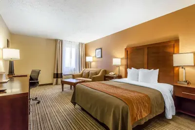 a hotel room with a large bed and a chair at Comfort Inn - Hall of Fame in Canton