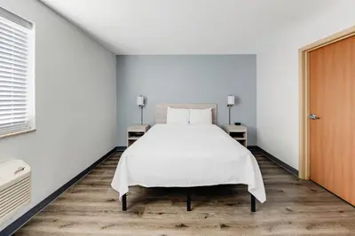 a bedroom with a white bed and two tables at Birch Hill Suites Dayton-WP AFB in Beavercreek