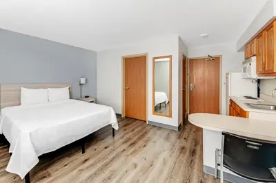 a hotel room with a bed and a kitchen at Birch Hill Suites Dayton-WP AFB in Beavercreek