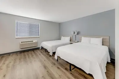 two beds in a room with white walls and wooden floors at Birch Hill Suites Dayton-WP AFB in Beavercreek