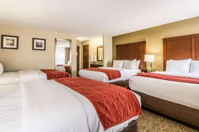 a hotel room with three beds with red and white sheets at Comfort Inn Norwalk - Sandusky in Norwalk
