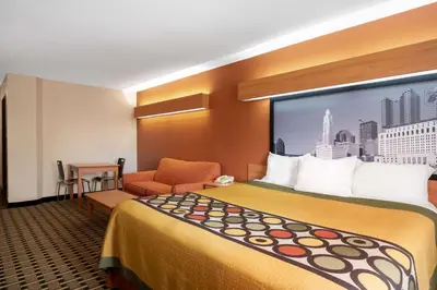 a hotel room with a large bed and a chair at Super 8 by Wyndham Columbus West in Columbus