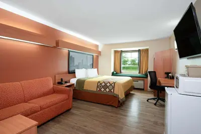 a hotel room with a bed and a couch at Super 8 by Wyndham Columbus West in Columbus