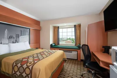 a hotel room with a bed and a desk and a window at Super 8 by Wyndham Columbus West in Columbus