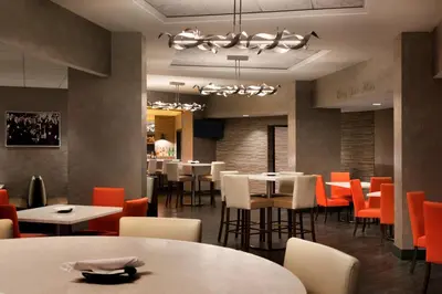 a restaurant with white tables and orange chairs at Radisson Hotel Cincinnati Riverfront in Covington