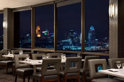 a restaurant with tables and chairs and a view of the city at Radisson Hotel Cincinnati Riverfront in Covington