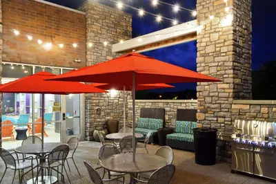 two tables and chairs with red umbrellas on a patio at Home2 Suites by Hilton Stow Akron in Stow