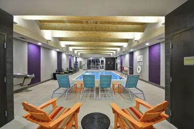 a pool room with chairs and a table and a swimming pool at Home2 Suites by Hilton Stow Akron in Stow