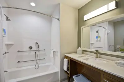a bathroom with a tub and a sink and a mirror at Home2 Suites by Hilton Stow Akron in Stow