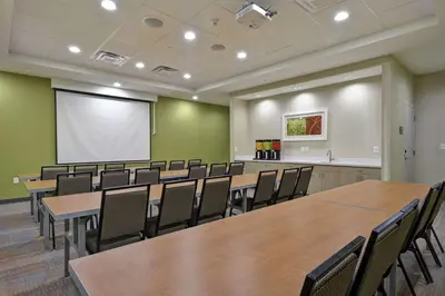 a conference room with tables and chairs and a white screen at Home2 Suites by Hilton Stow Akron in Stow