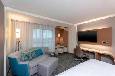 a hotel room with a bed and a couch and a tv at Courtyard by Marriott Cleveland Elyria in Elyria