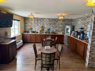 a kitchen with two tables and chairs and a counter at Best Western Norwalk in Norwalk