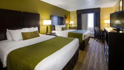 a hotel room with two beds and a flat screen tv at Best Western Norwalk in Norwalk