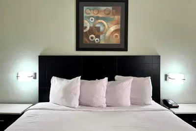 a bed with white pillows and a painting above it at Baymont by Wyndham Cincinnati Sharonville in Sharonville