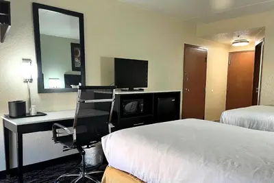 a hotel room with a bed and a desk with a mirror at Baymont by Wyndham Cincinnati Sharonville in Sharonville