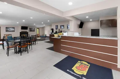 a restaurant with a bar and tables and chairs at Super 8 by Wyndham Bridgeport/Clarksburg Area in Bridgeport