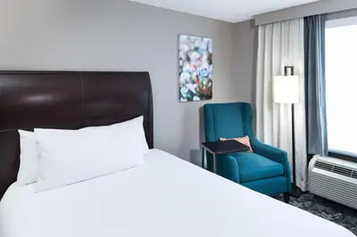 a bedroom with a bed and a blue chair at Hilton Garden Inn Cincinnati/Mason in Mason