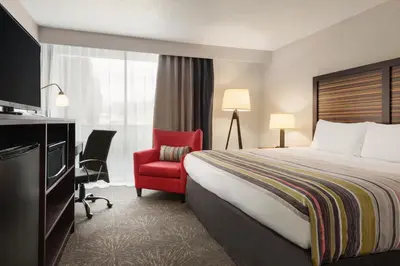 a hotel room with a bed and a red chair at Country Inn & Suites by Radisson, Erlanger - Cincinnati South in Erlanger