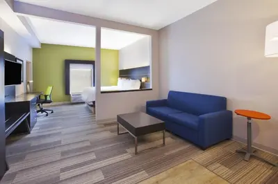 a living room with a blue couch and a bed at Holiday Inn Express Tiffin by IHG in Tiffin