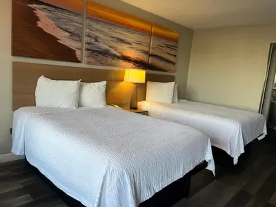 a hotel room with two beds and a painting on the wall at Days Inn & Suites by Wyndham Dayton North in Dayton