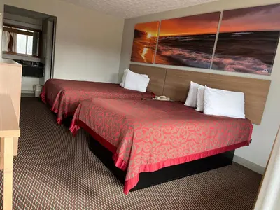 a hotel room with two beds and a painting on the wall at Days Inn & Suites by Wyndham Dayton North in Dayton