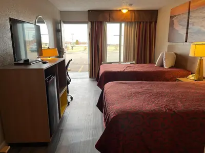 a hotel room with two beds and a flat screen tv at Days Inn & Suites by Wyndham Dayton North in Dayton