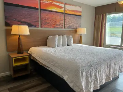 a bedroom with a white bed with two lamps and a window at Days Inn & Suites by Wyndham Dayton North in Dayton