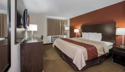 a hotel room with a bed and a flat screen tv at Red Roof Inn Dayton Huber Heights in Dayton