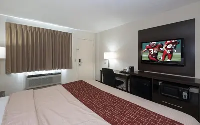 a hotel room with a bed and a flat screen tv at Red Roof Inn Dayton Huber Heights in Dayton