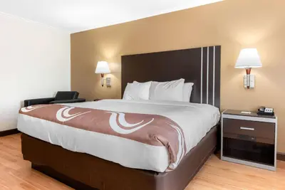 a hotel room with a large bed and a chair at Quality Inn Fairborn near Wright Patterson AFB in Fairborn