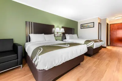 a hotel room with two beds and a chair at Quality Inn Fairborn near Wright Patterson AFB in Fairborn