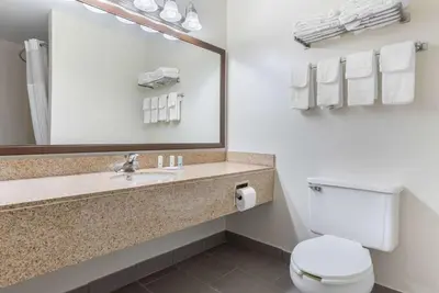 a bathroom with a toilet and a sink with a mirror at Quality Inn Fairborn near Wright Patterson AFB in Fairborn