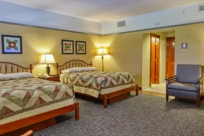 a hotel room with two beds and a chair at Carlisle Inn Walnut Creek in Walnut Creek