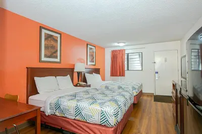 a hotel room with two beds and an orange wall at Motel 6-Dayton, OH - Englewood in Englewood