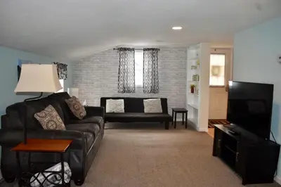 a living room with a black couch and a television at Cozy 2nd story Flat near downtown in Adrian
