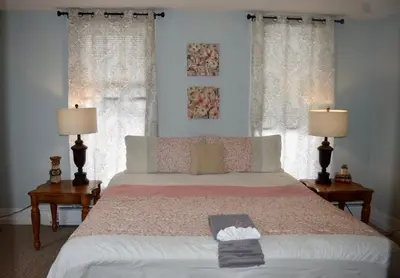 a bedroom with a bed with two lamps and two windows at Cozy 2nd story Flat near downtown in Adrian