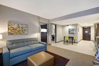 a living room with a blue couch and a dining room at Home2 Suites By Hilton Columbus Airport East Broad in Columbus