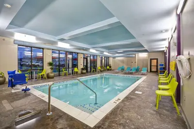 a pool in a hotel room with chairs and tables at Home2 Suites By Hilton Columbus Airport East Broad in Columbus